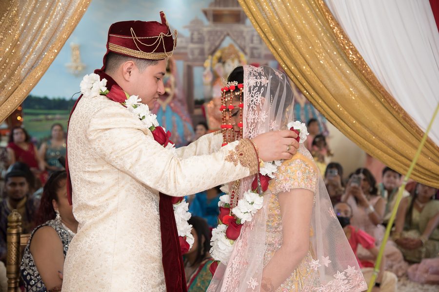 Groom placing a flower garland on the bride during a traditional ceremony