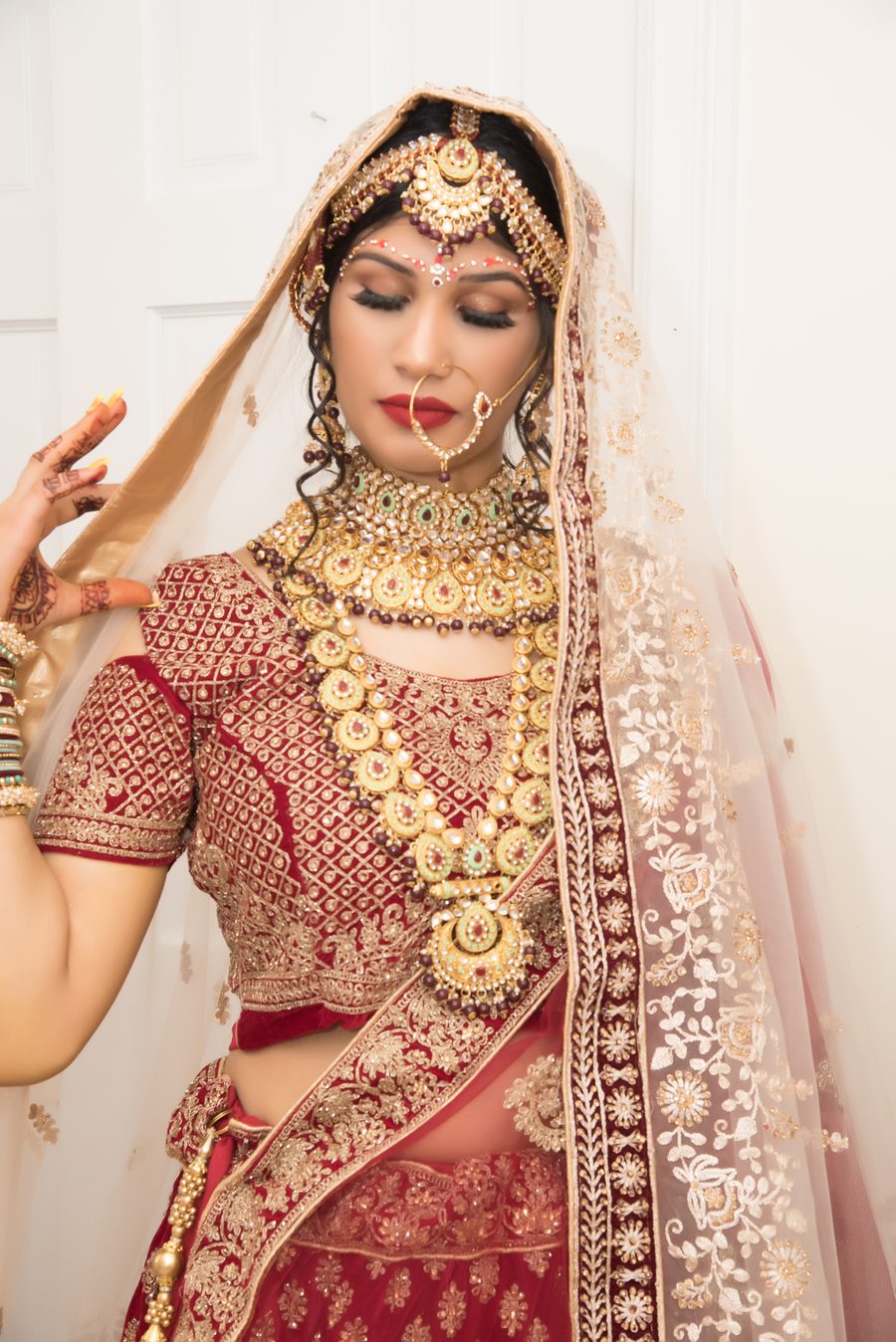 Bride in an embellished red and gold lehenga with traditional jewelry