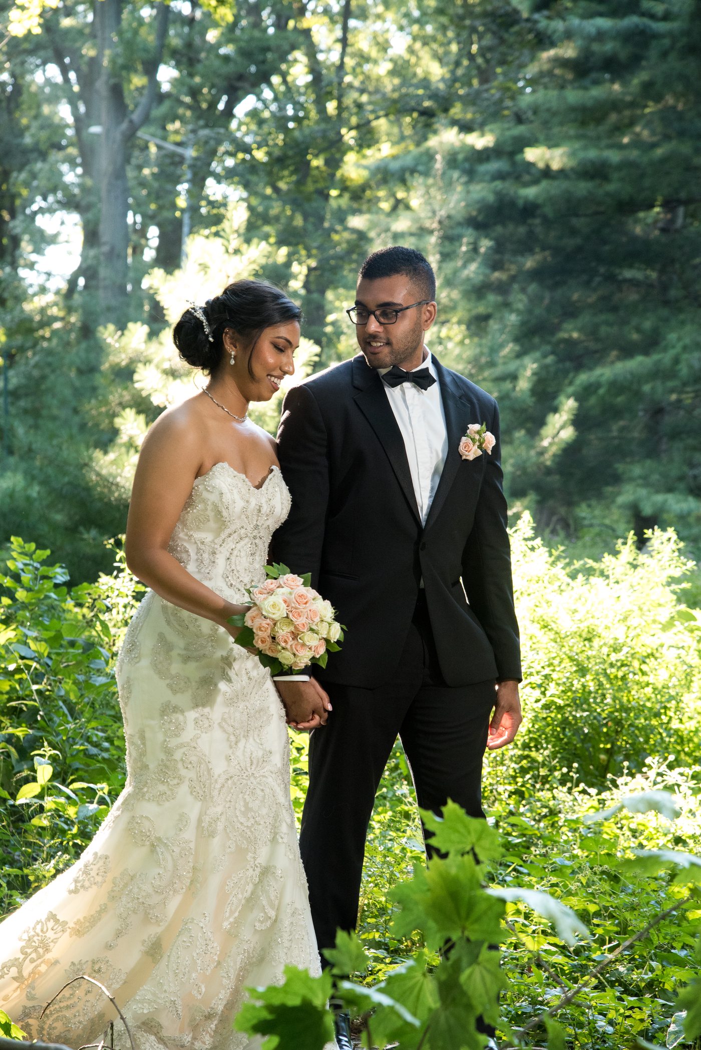 Bride and groom walking hand in hand through a sunlit garden
