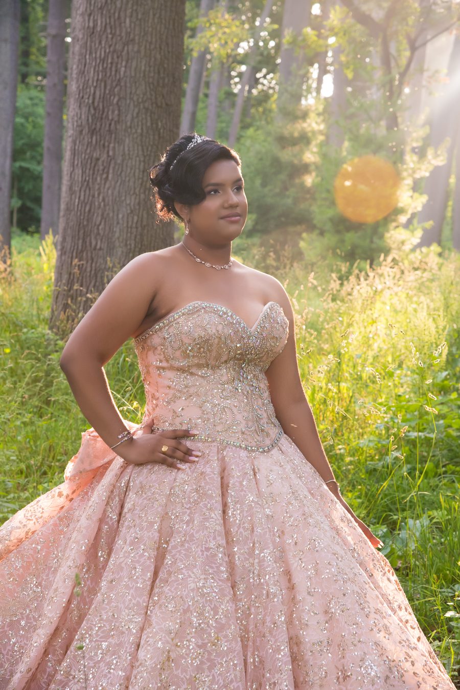 Quinceañera in a blush beaded gown in golden forest light