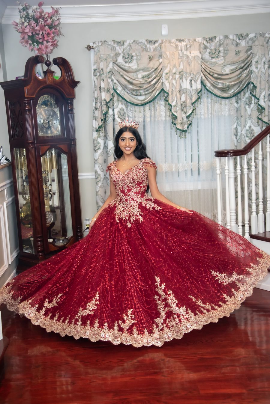 Quinceañera in a red and gold gown with a crown, skirt in full twirl