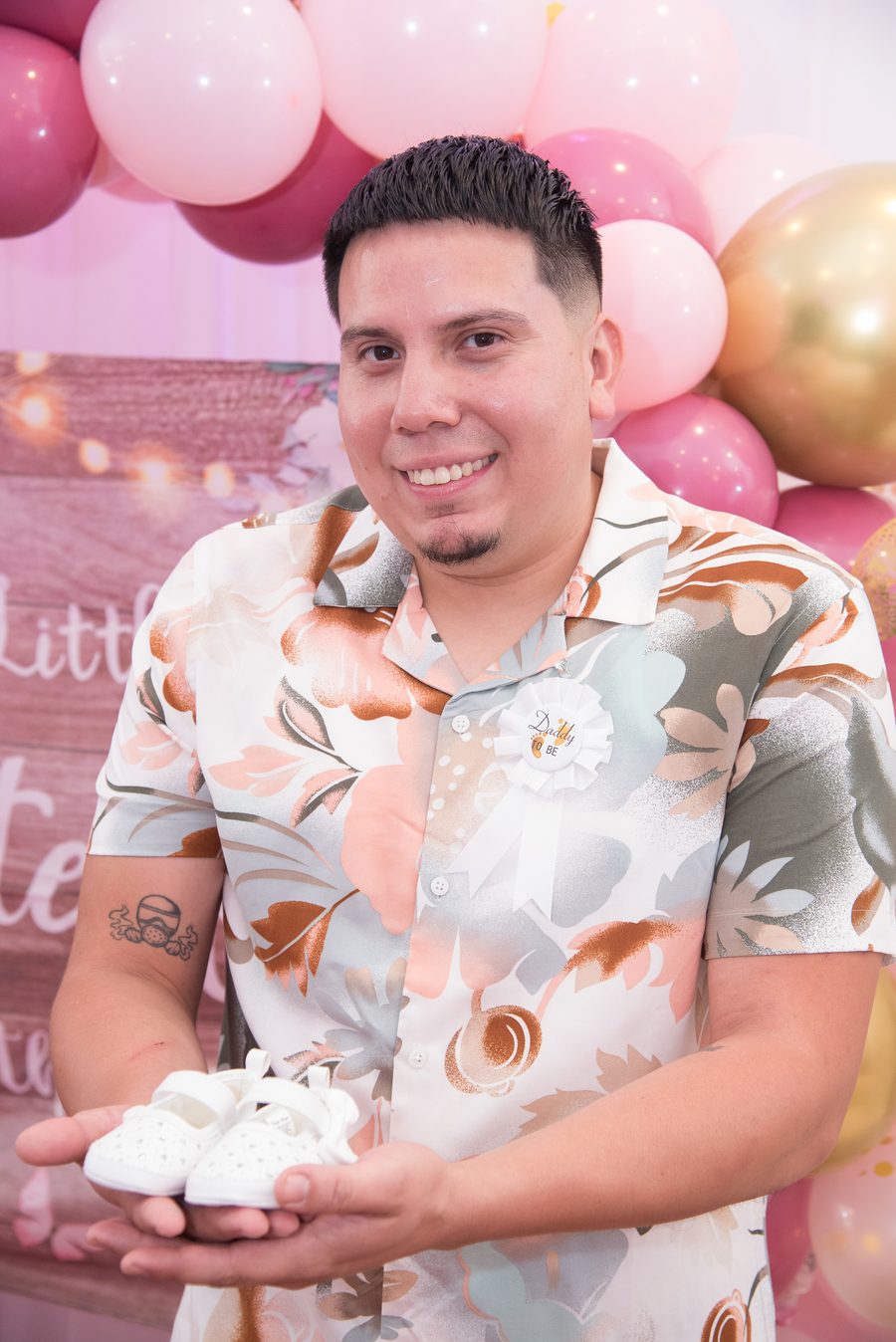 Father-to-be smiling while holding a pair of tiny baby shoes