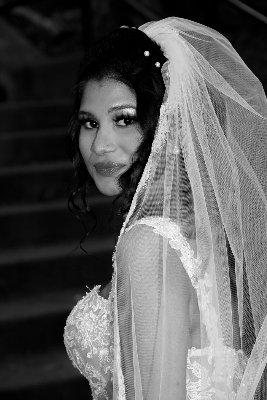 Black and white portrait of a bride glancing over her shoulder beneath her veil